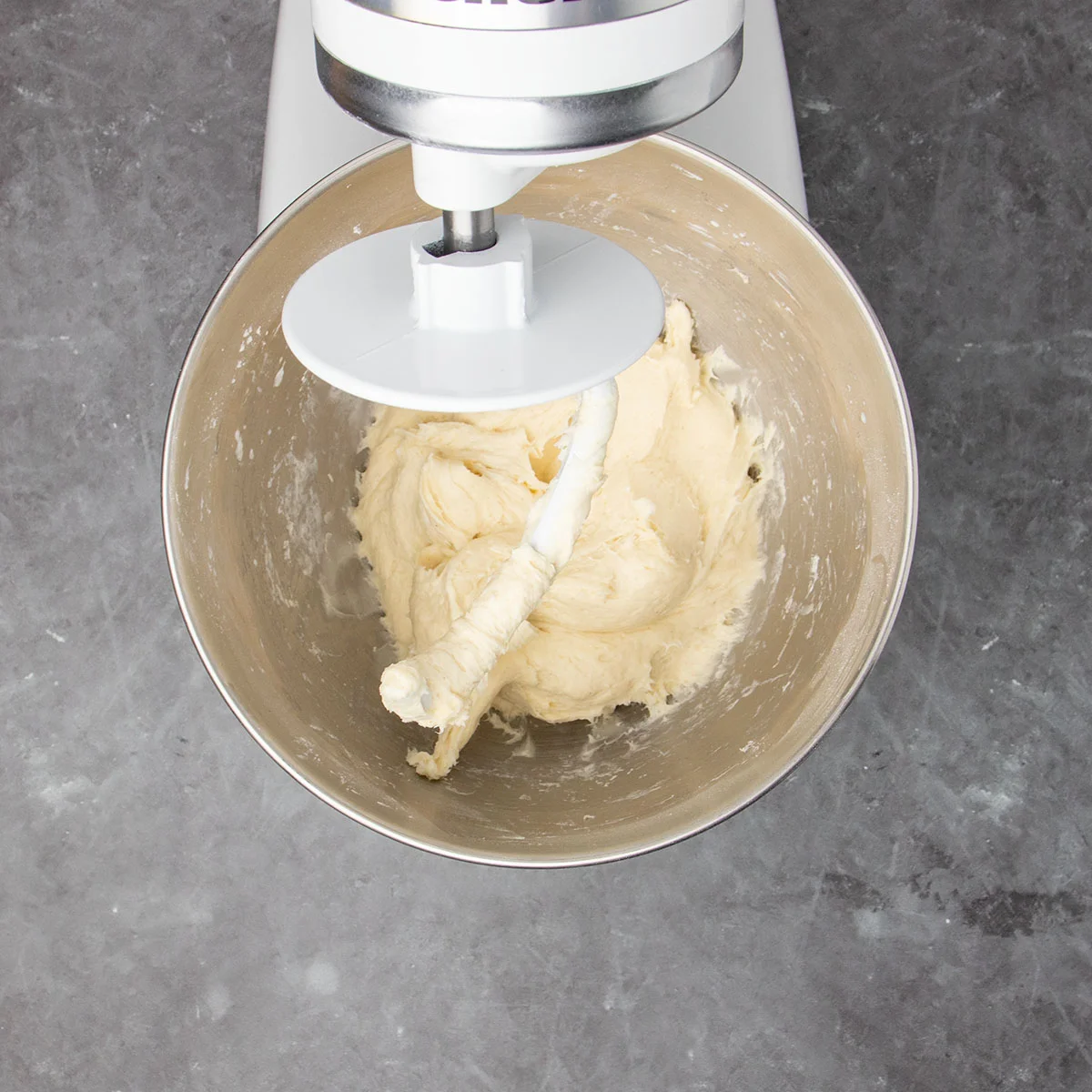 stand mixer bowl in white kitchenaid stand mixer with sticky pale dough with white dough hook