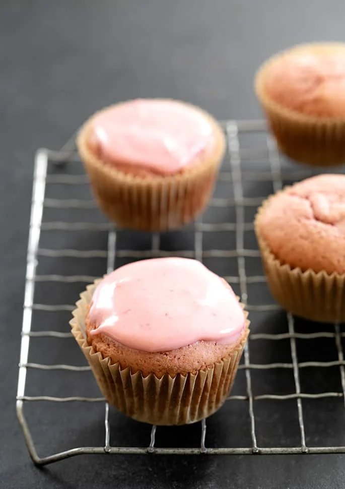 Strawberry cupcakes glazed and unglazed on wire rack