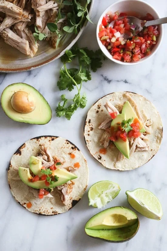 Tacos made with shredded pork, avocado, and salsa