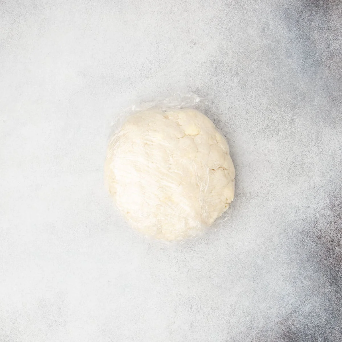 Tan scone dough wrapped in plastic wrap and ready to chill.