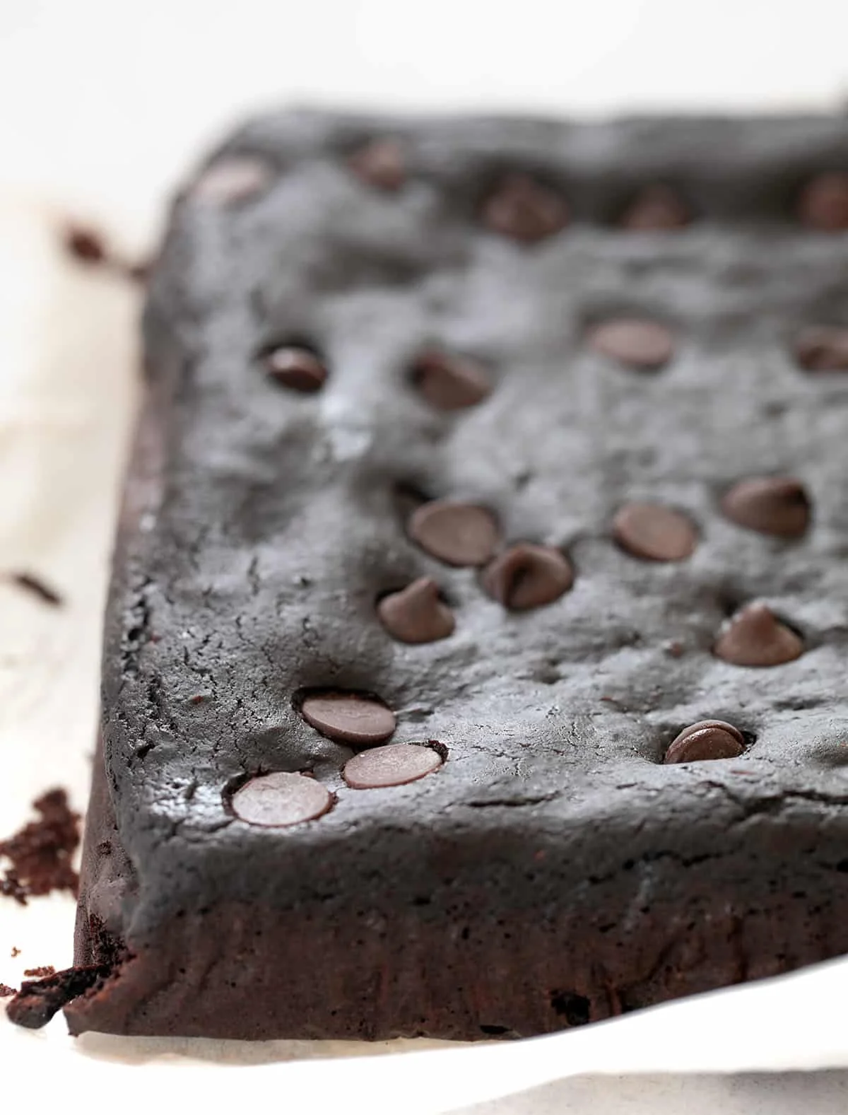 The brownies out of pan uncut on white paper.