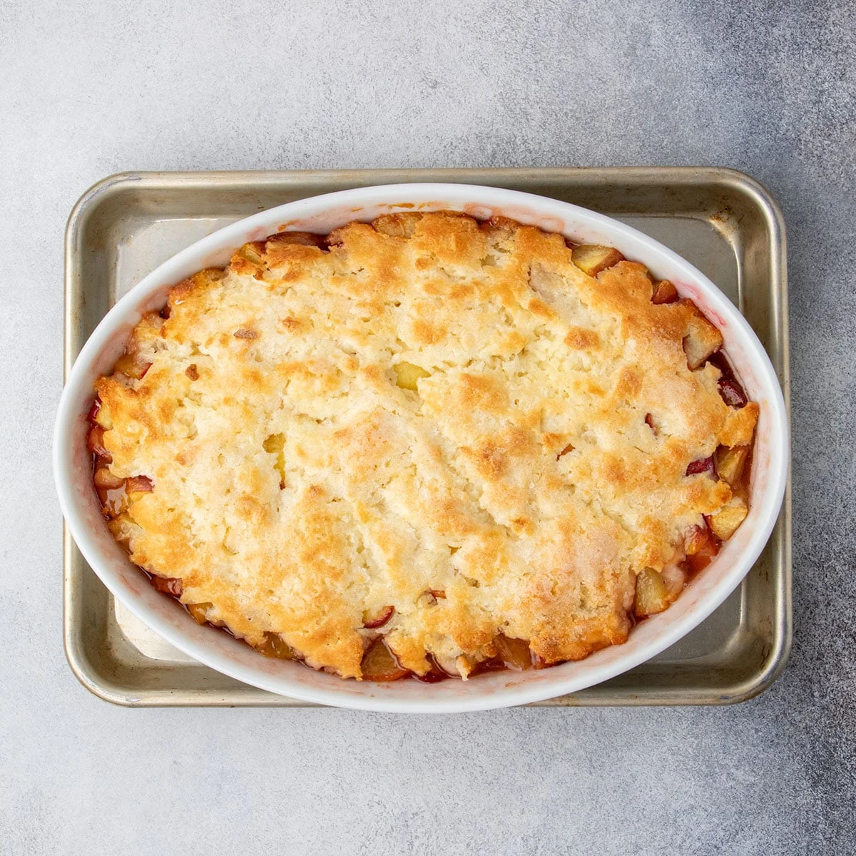 The cobbler fresh from the oven, with a golden brown, crisp topping and bubbling peach filling around the edges.
