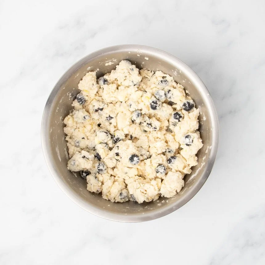 The mixture in the bowl after being stirred, with wet and dry ingredients combined into a crumbly dough.