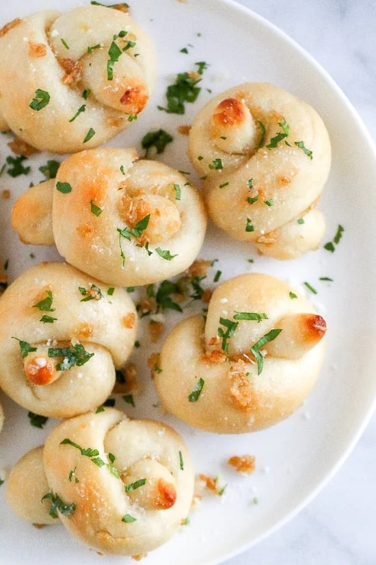 These soft, garlicky knots taste just like your favorite pizzeria’s garlic knots, but made from scratch using my easy yeast-free bagel dough recipe (just flour, Greek yogurt, baking powder and salt).