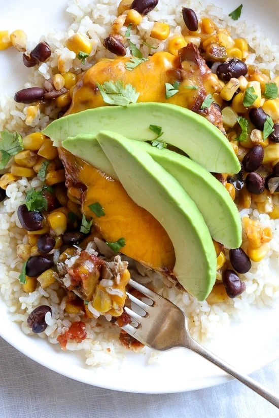 This EASY Slow Cooker Chicken dish is cheesy and delicious, made with boneless chicken breast, black beans, corn and salsa topped with melted cheddar cheese. YUM!