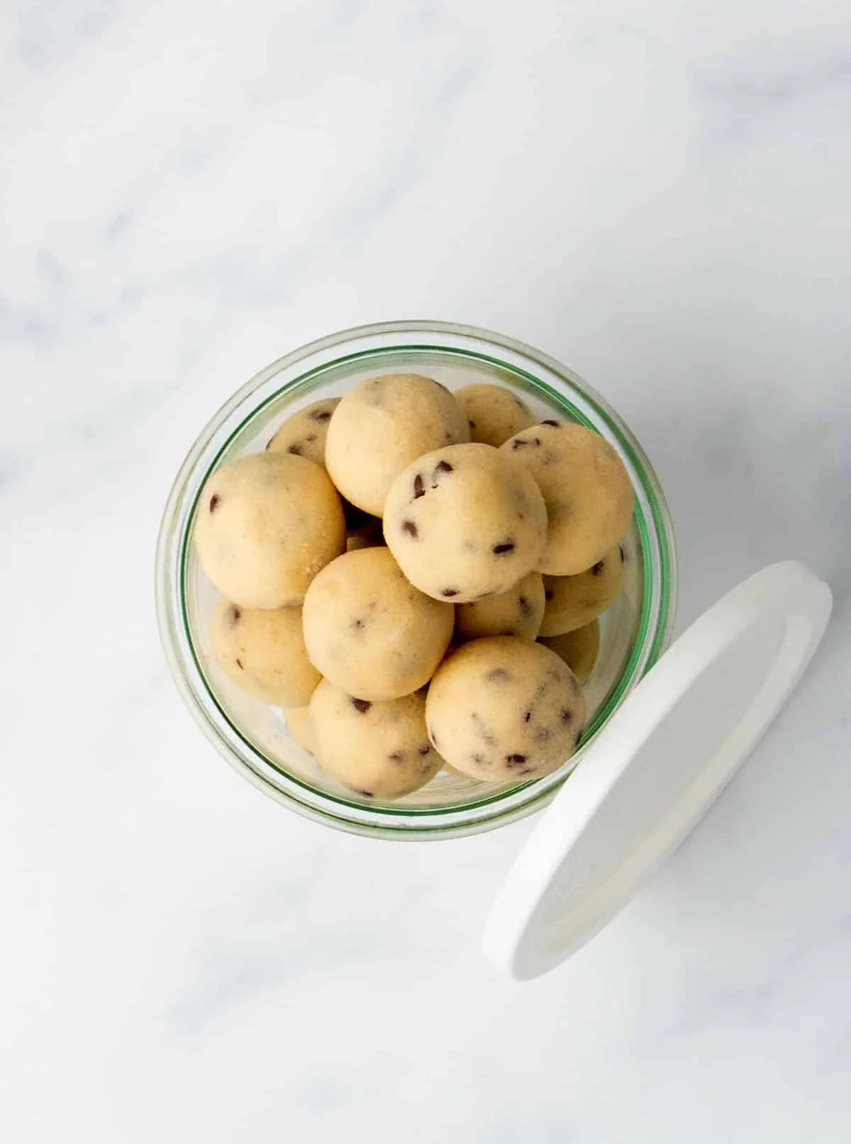 Top-down view of a glass jar filled with chocolate chip cookie dough balls.