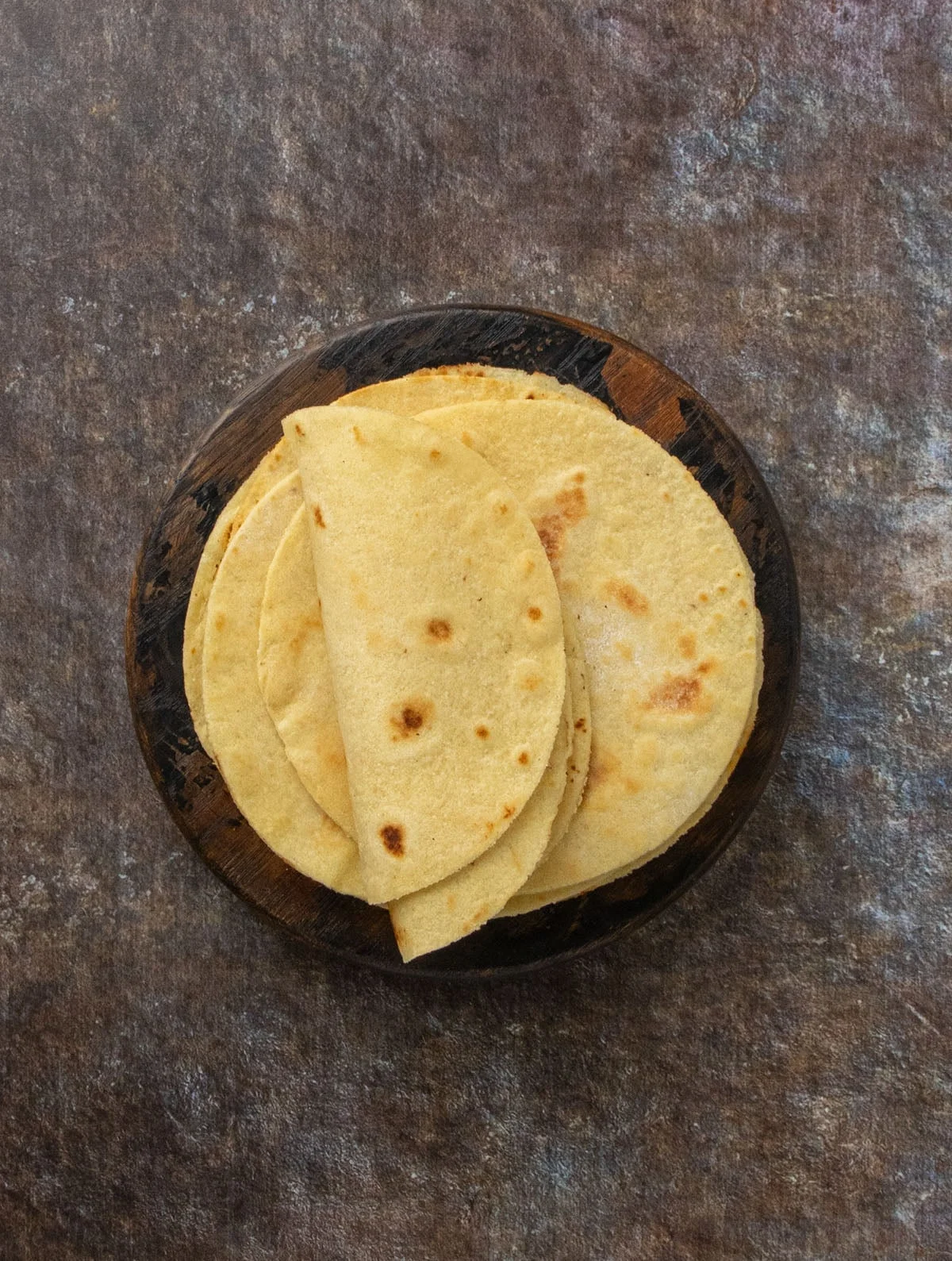 Top-down view of golden tortillas arranged neatly on a dark background.