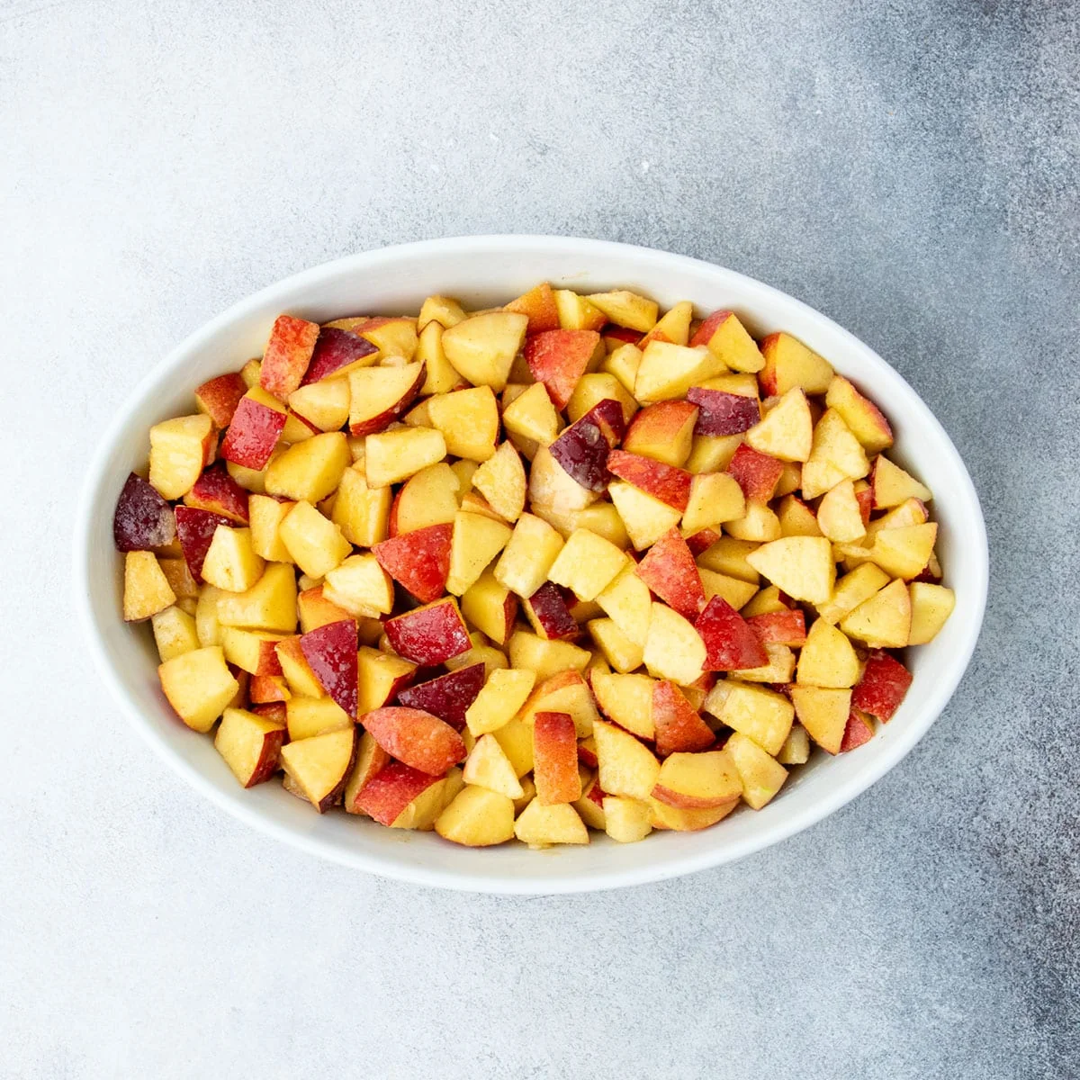 Tossed filling spread evenly in a white oval baking dish.