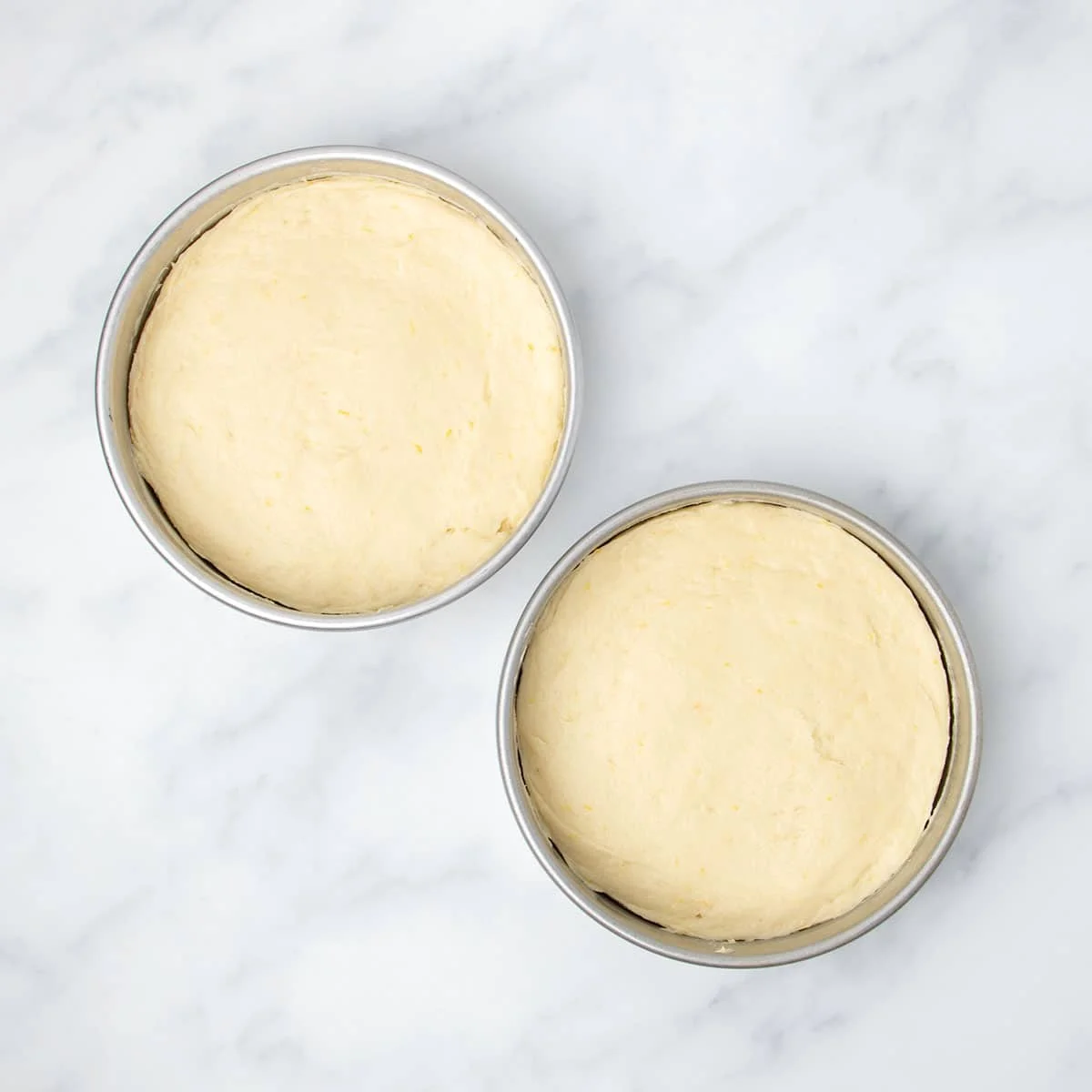 two 8-inch round metal cake pans with half of the cake batter in each, smooth on top