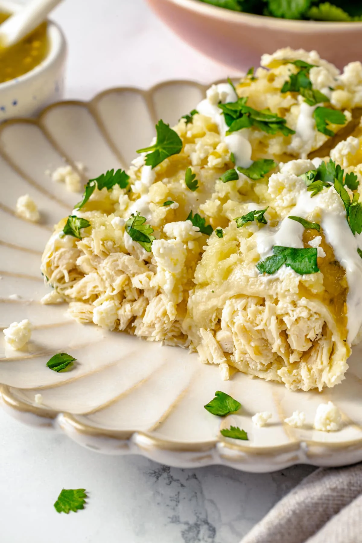 Two green chicken enchiladas on a plate with the ends off to show the chicken inside