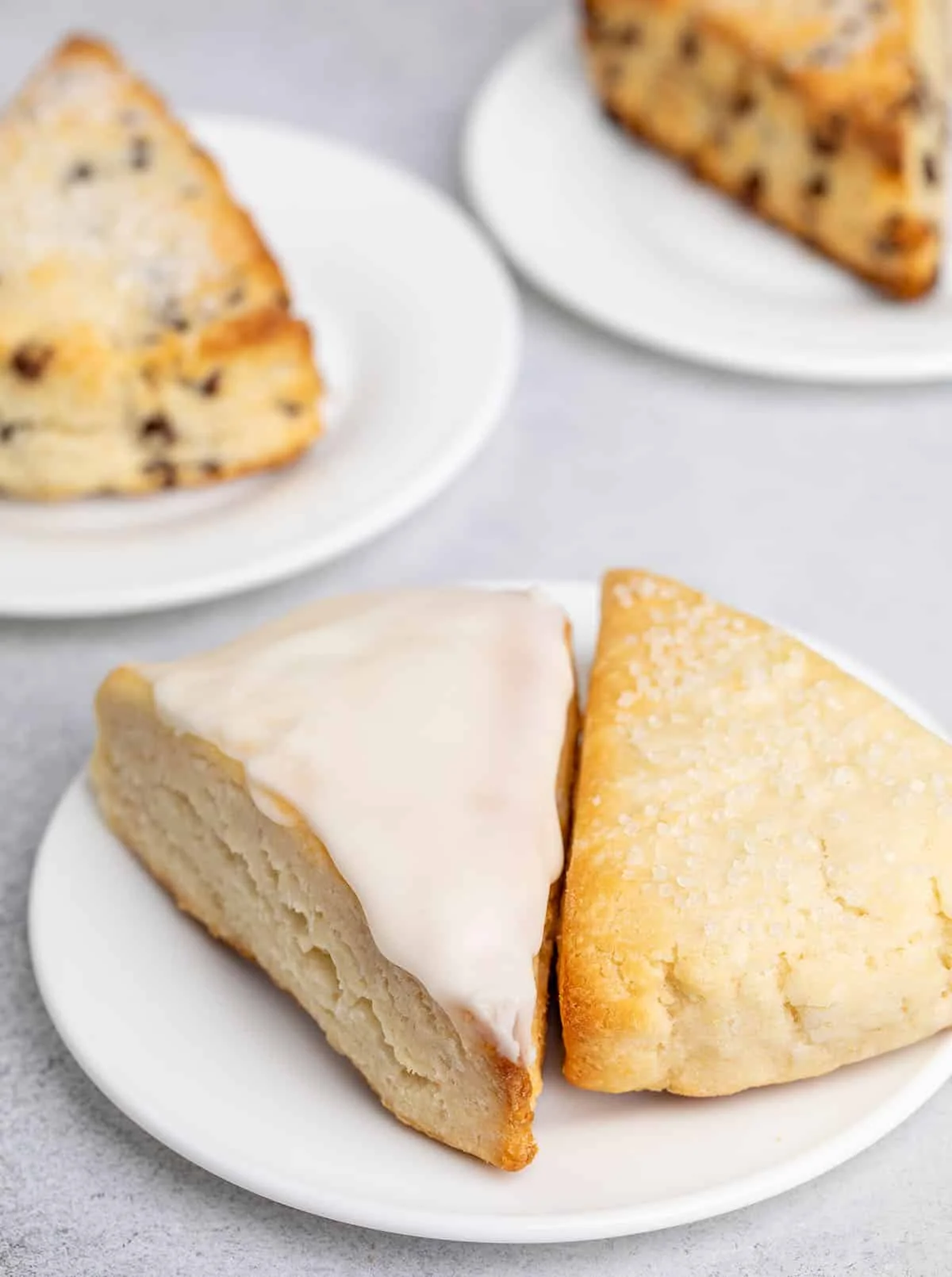 Two scones on a white plate, one glazed and one topped with coarse sugar.