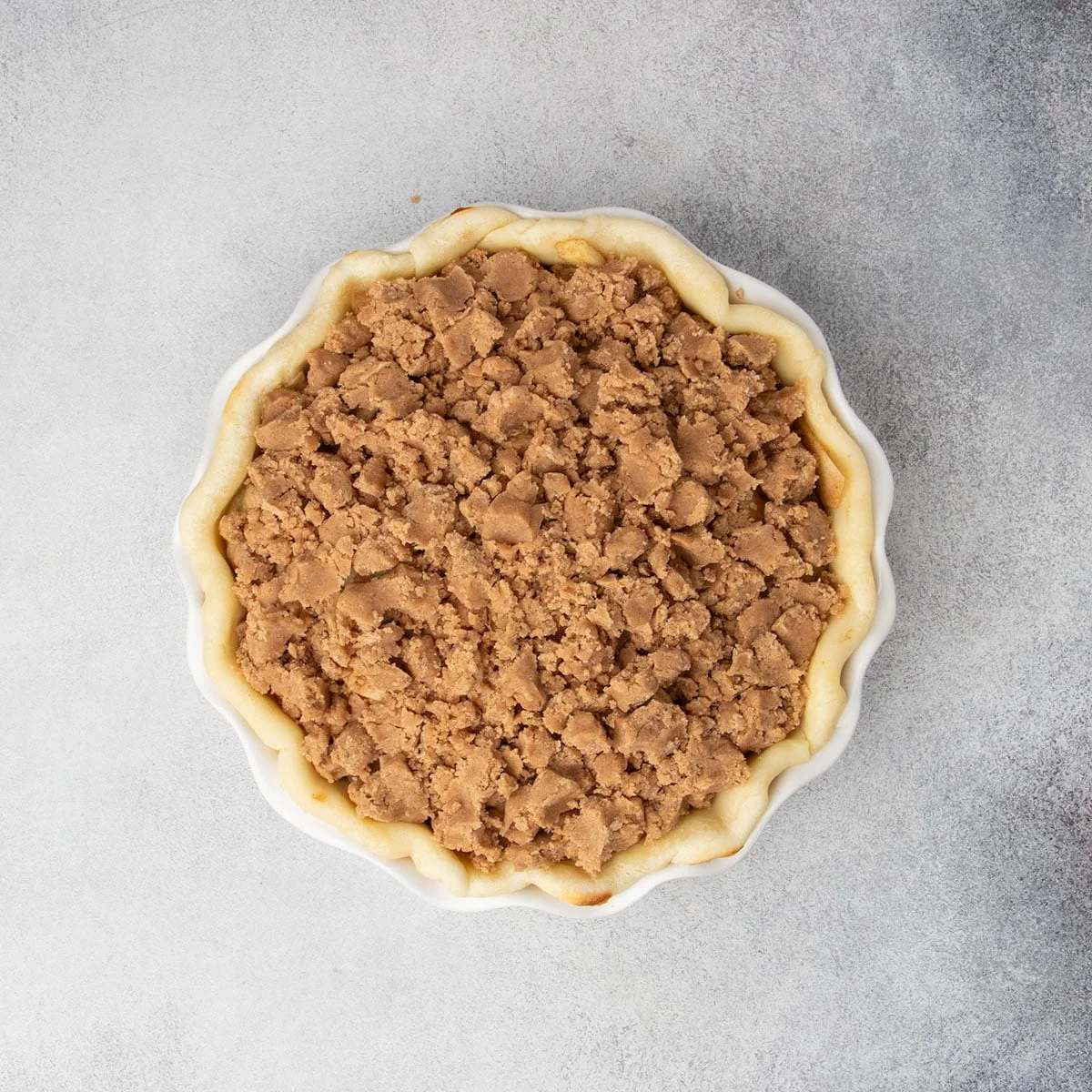 Unbaked apple pie filled with seasoned apples and topped with a crumb mixture. 
