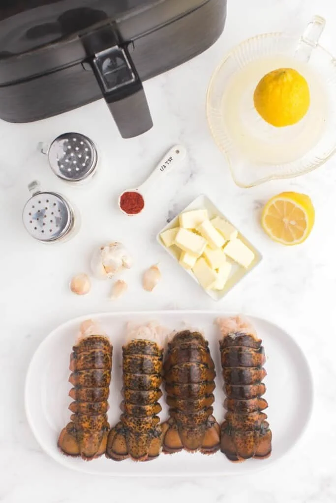 Uncooked lobster tails next to other recipe ingredients.