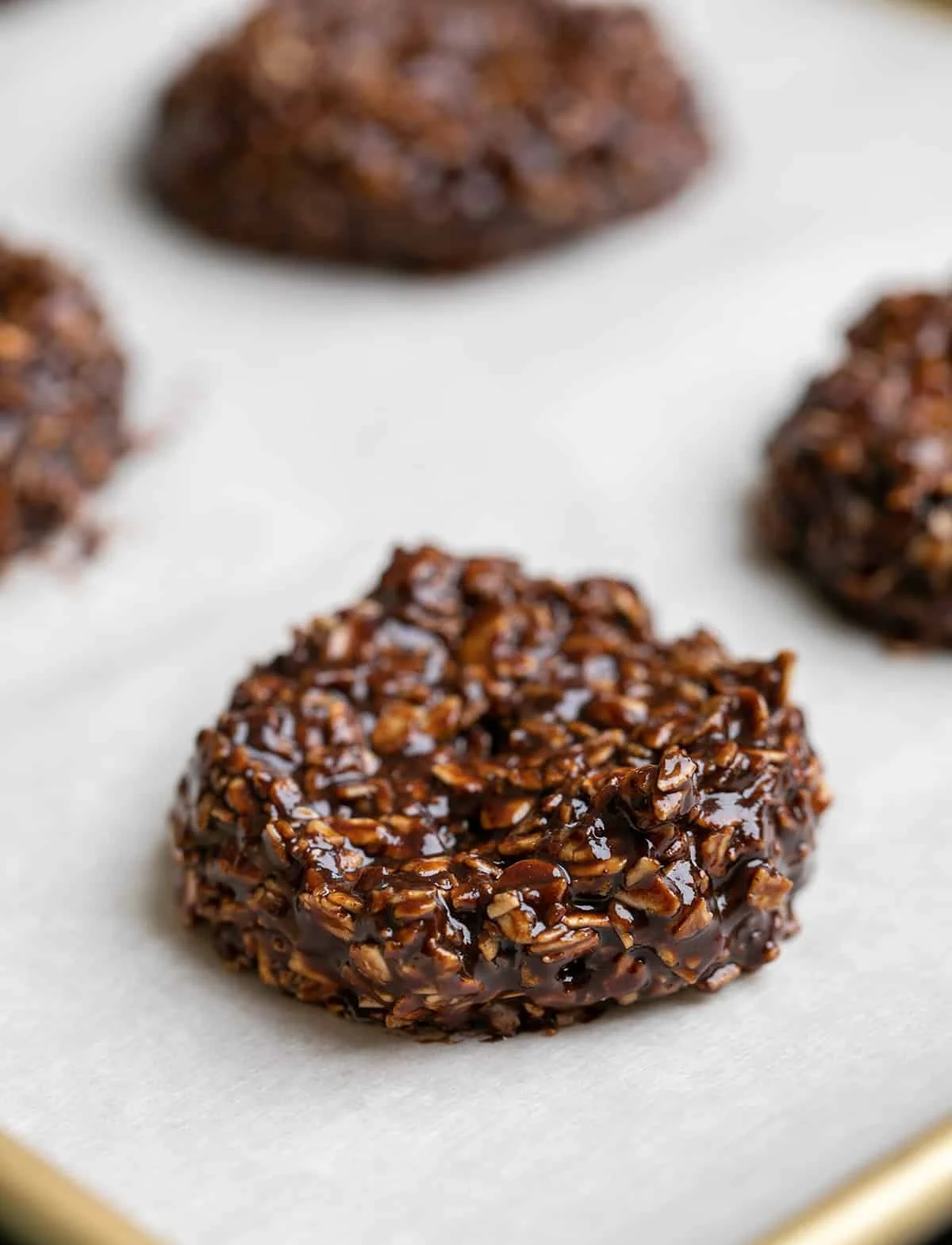 Wet chocolate oat cookies on white paper on tray