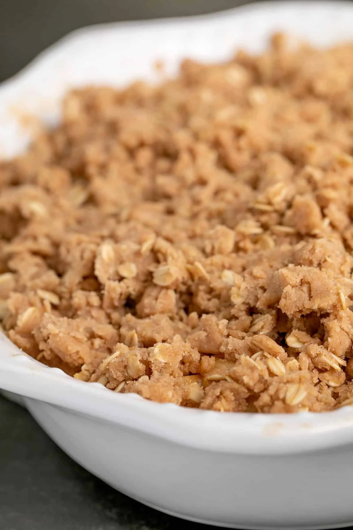 White oval baking dish with raw brown crisp topping.