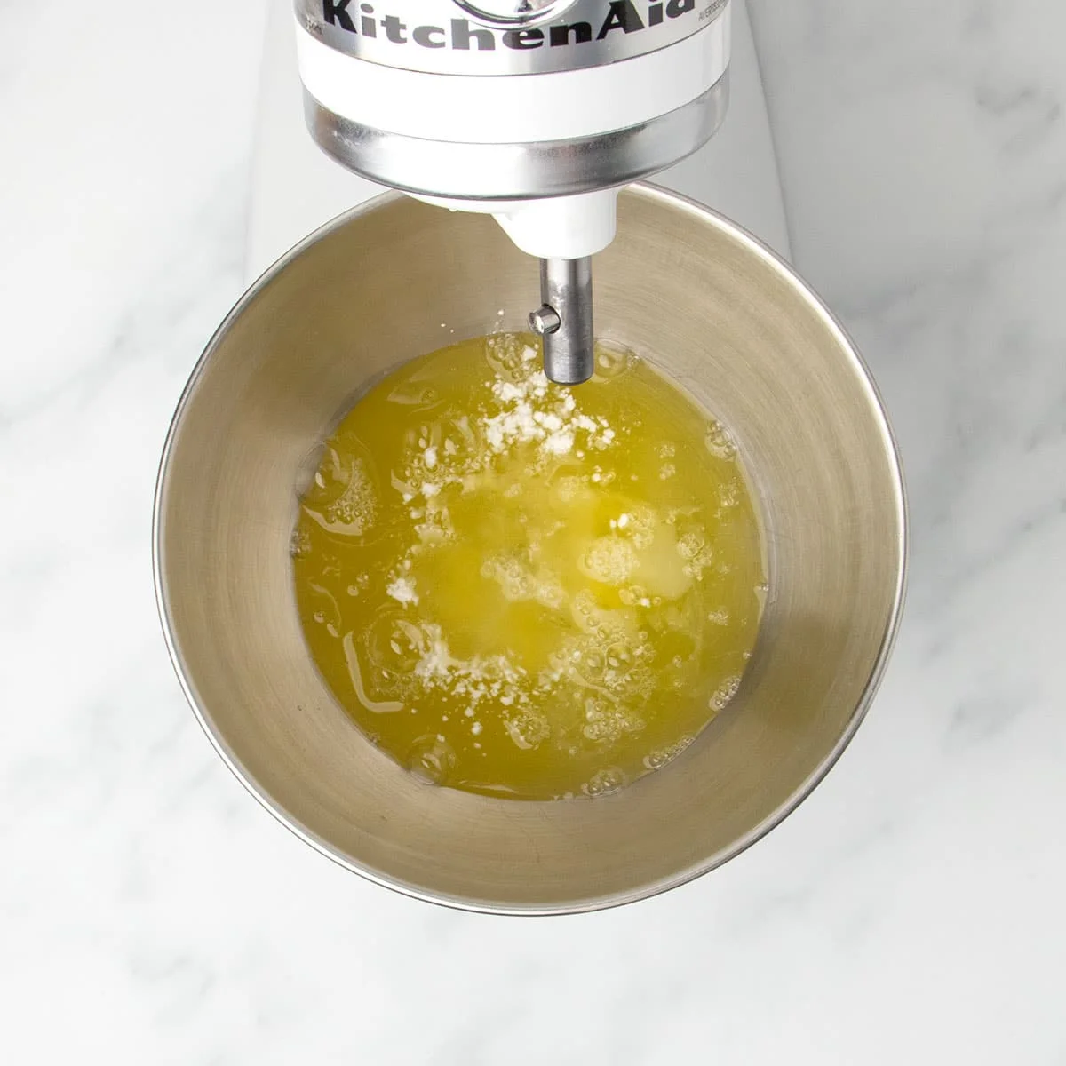 white stand mixer with round metal mixing bowl with egg whites and cream of tartar