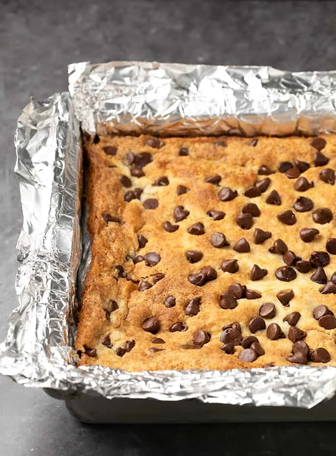 Whole baked pumpkin dump cake with chocolate chips in foil lined square baking pan