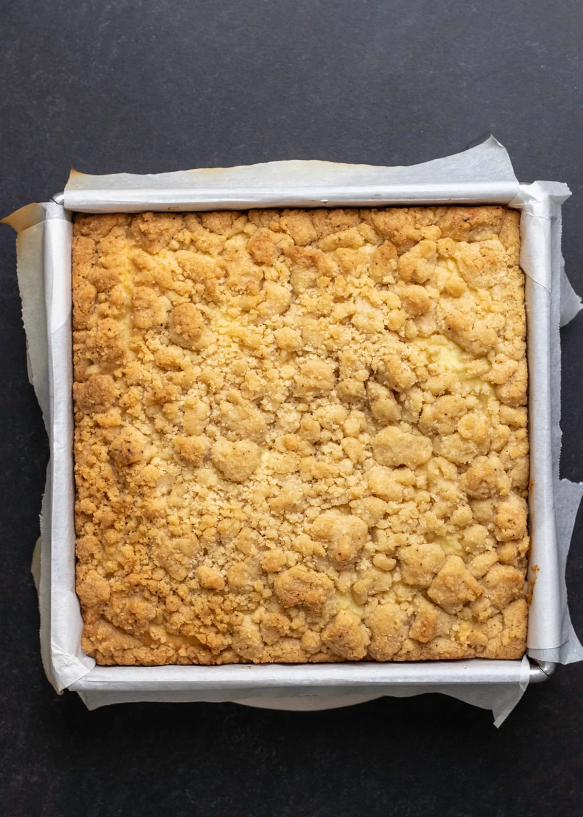 whole gluten free coffee cake in white paper in square metal baking tin