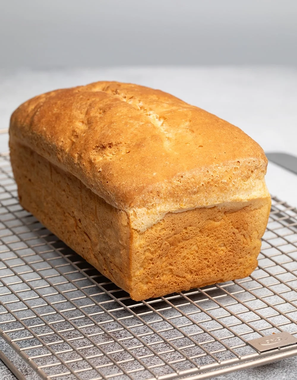 Whole loaf of light brown bread with Caputo flour on wire rack