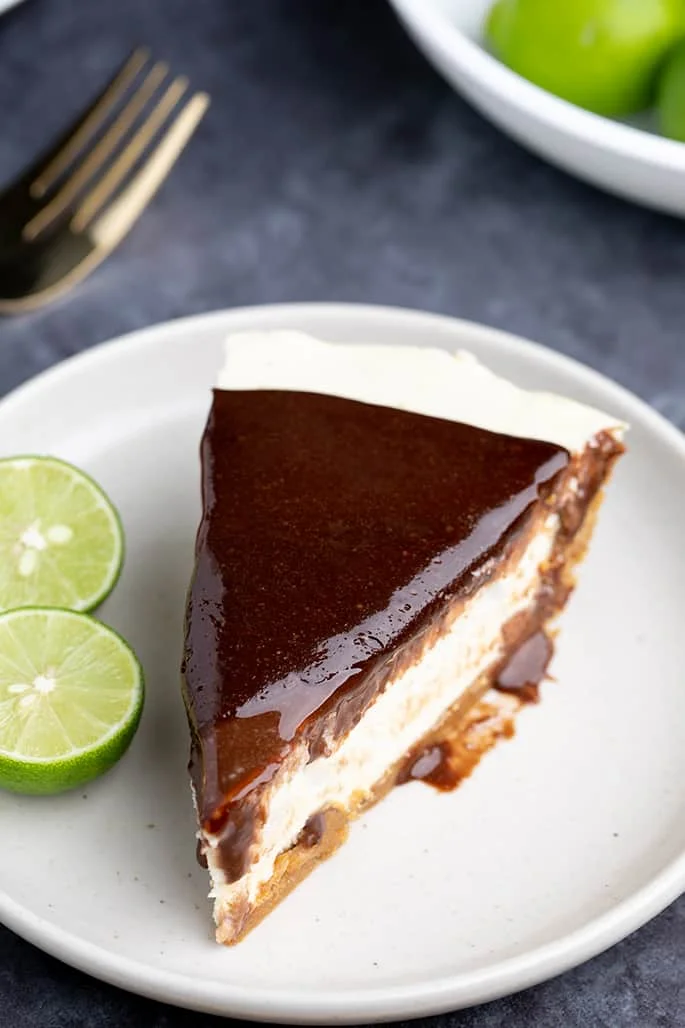 Whole slice of pie on white plate with cut key lime