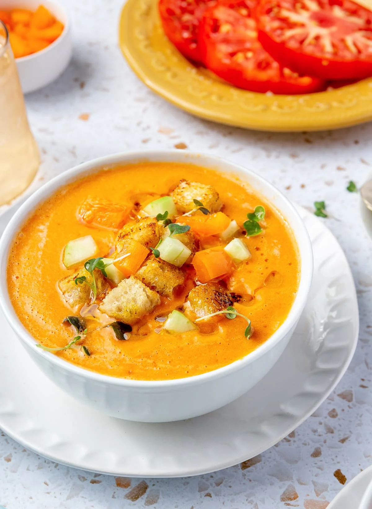 A bowl of gazpacho topped with fresh chopped cucumber, tomato, and crunchy croutons.