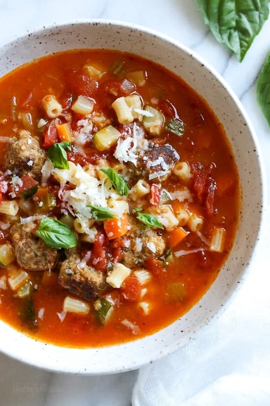 A bowl of turkey meatball and ditalini soup topped with shredded cheese
