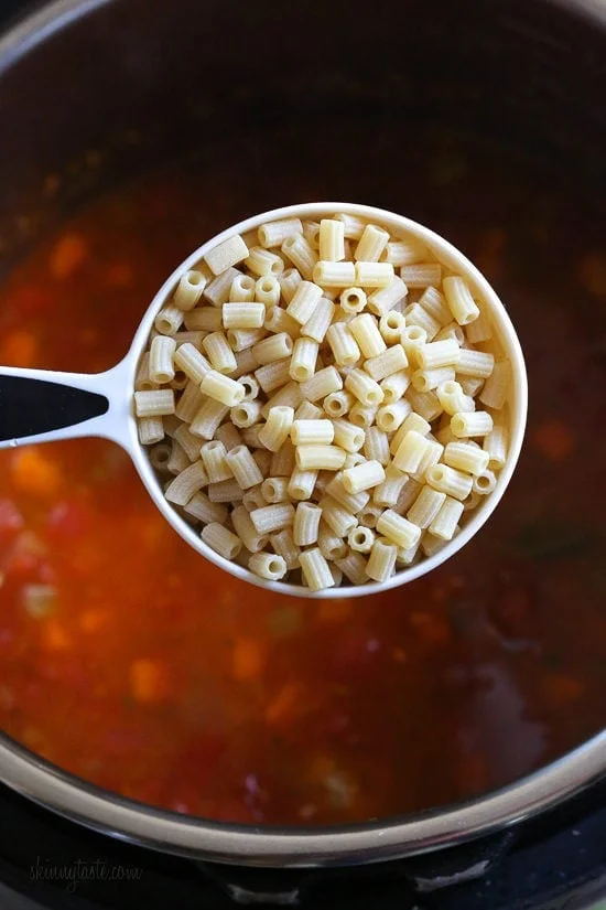 A cup of ditalini held over turkey meatball soup