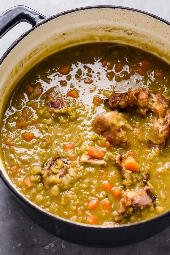 A dutch oven with split pea soup and ham.