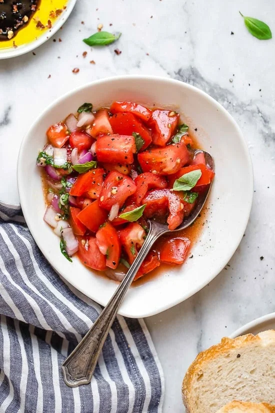 Bowl of summer tomato salad with spoon.