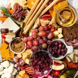 Charcuterie and cheese board with fruit, olives, and spreads.