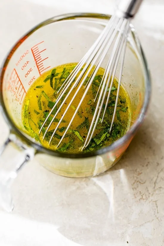 Citrus dressing in a measuring cup with a whisk.