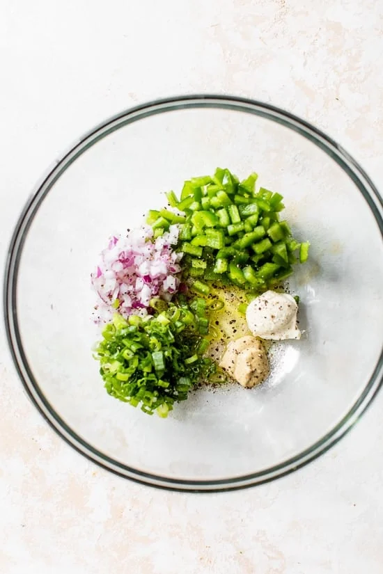 Dijon, scallions, mayo, red onion in a bowl.