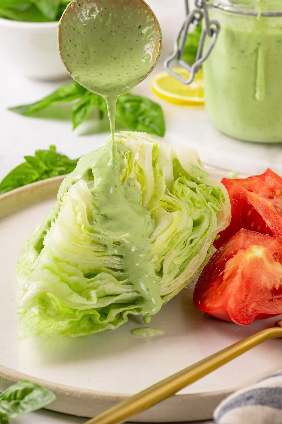 Drizzling basil green goddess dressing over wedge salad