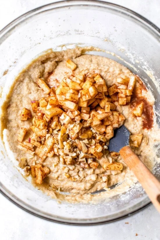 Folding diced apples and walnuts into apple bread batter.