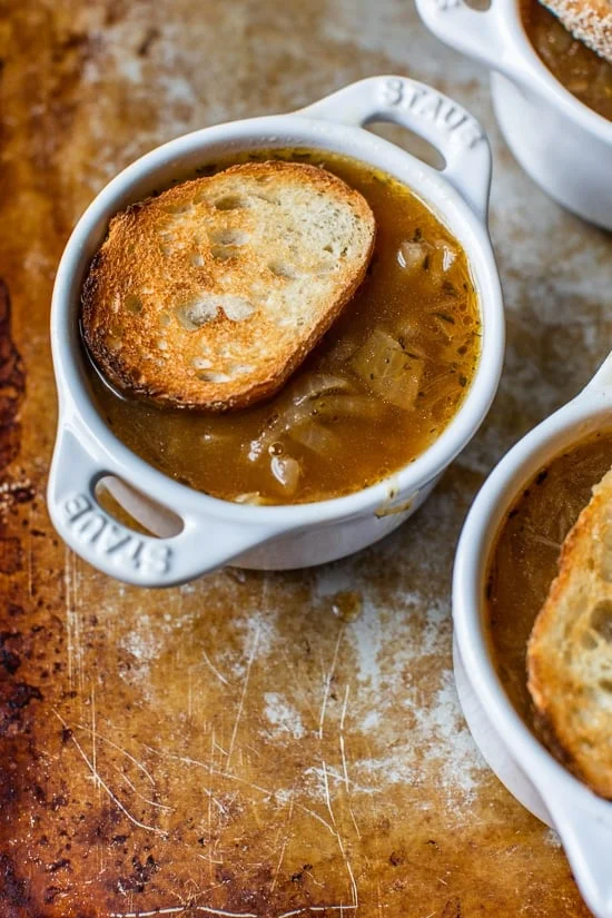 French onion soup topped with a slice of toasted bread in a ramekin.