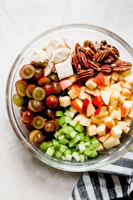 Ingredients for chicken Waldorf salad in glass bowl.