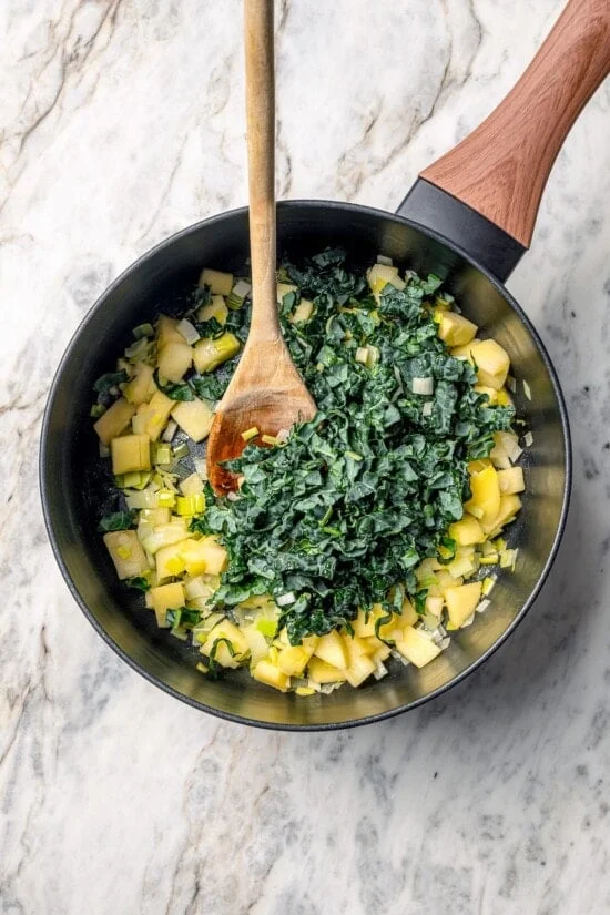 Kale added to pan of leeks and apples.