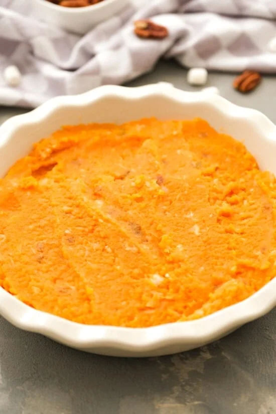 Mashed sweet potatoes spread inside a round baking dish.