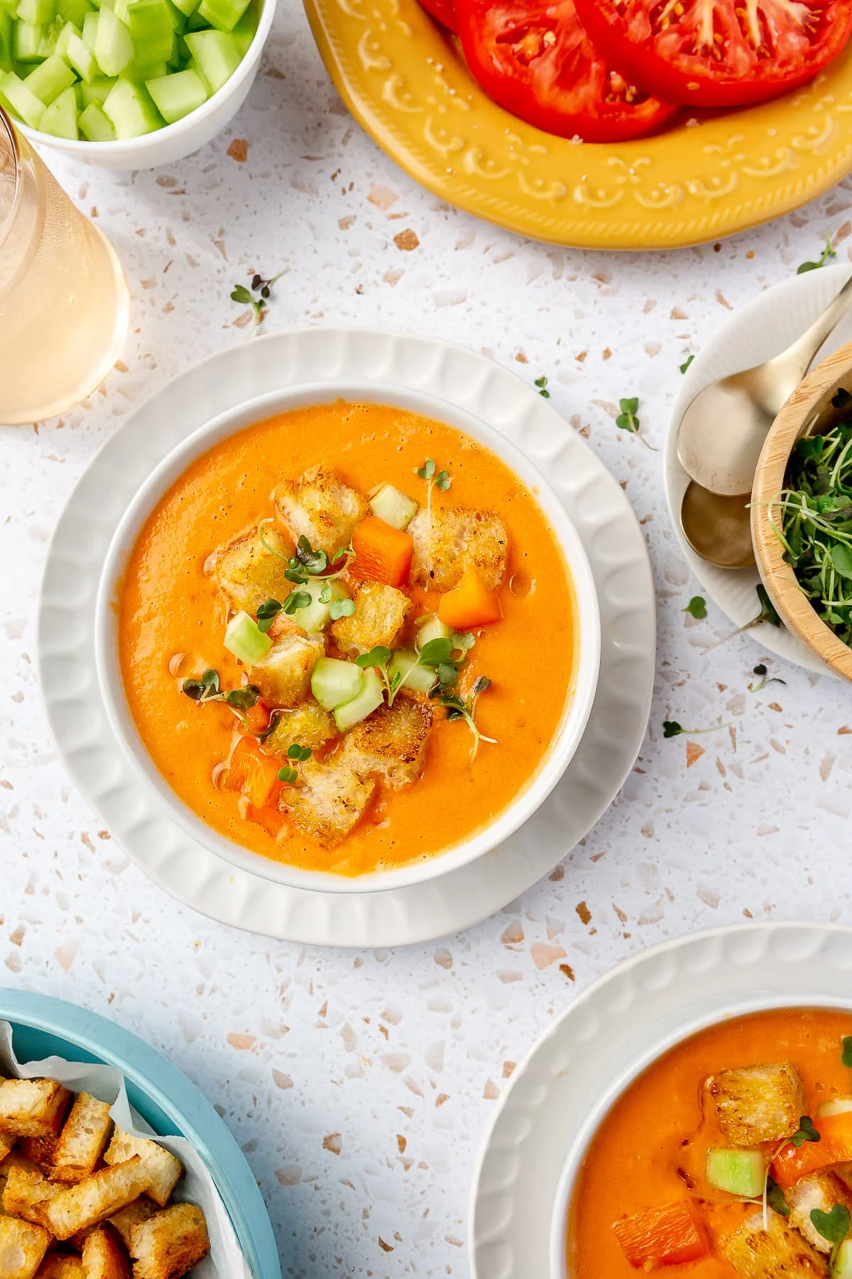 Overhead view of a bowl of gazpacho topped with fresh chopped cucumber, tomato, and crunchy croutons.