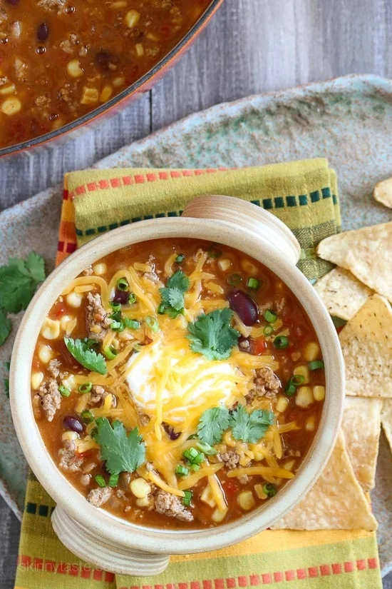 Overhead view of a bowl of turkey taco soup with sour cream, cheese, and cilantro.