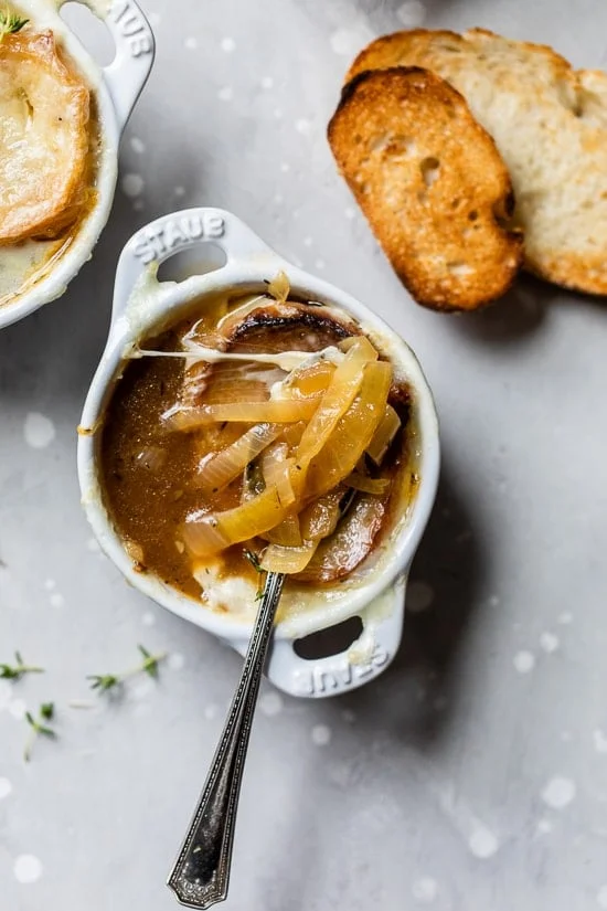 Overhead view of a spoon resting in a bowl of French onion soup.