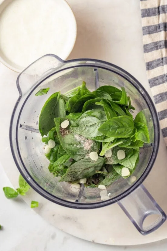 Overhead view of ingredients for basil green goddess dressing added to blender