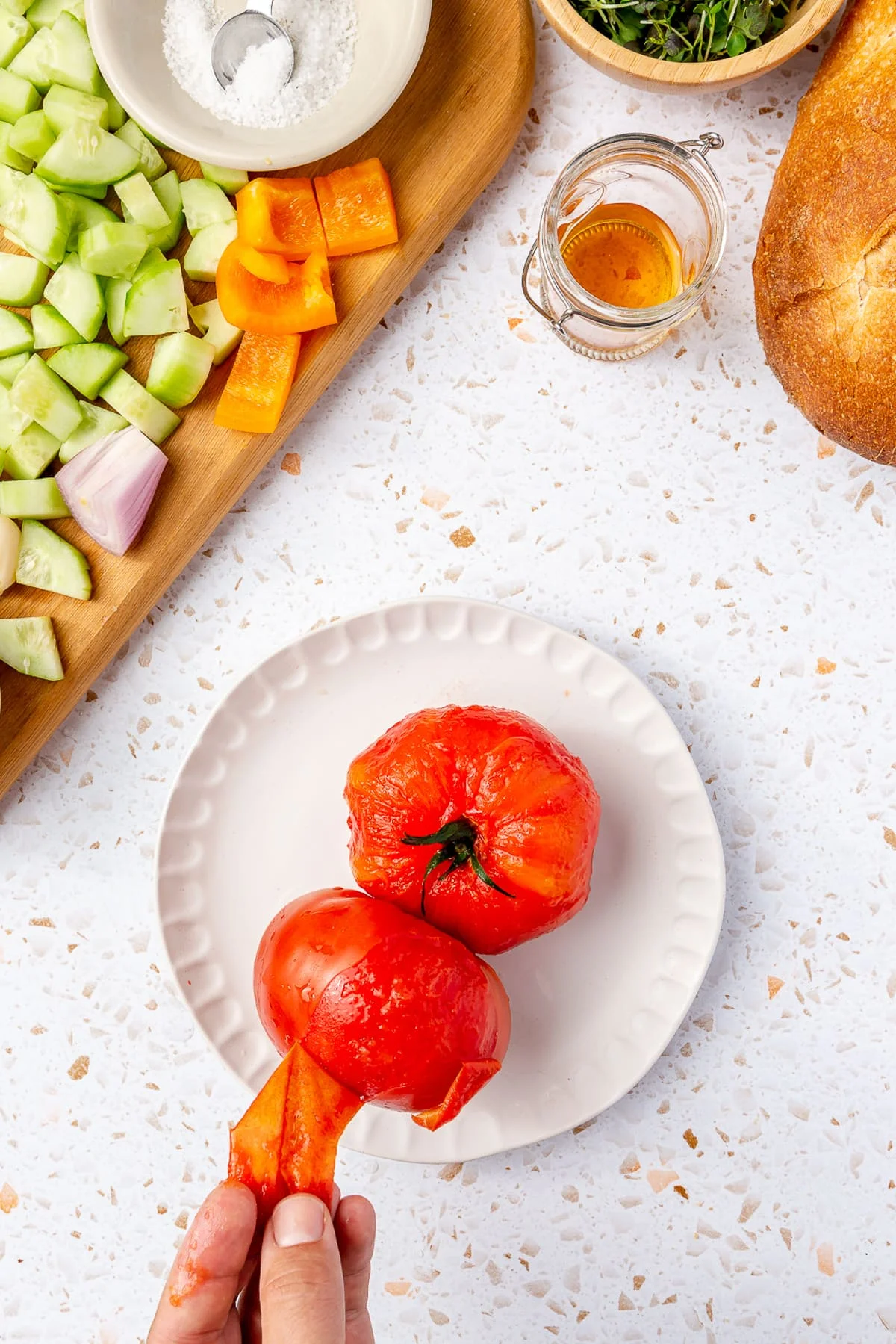 Peeling blanched tomatoes in a bowl.