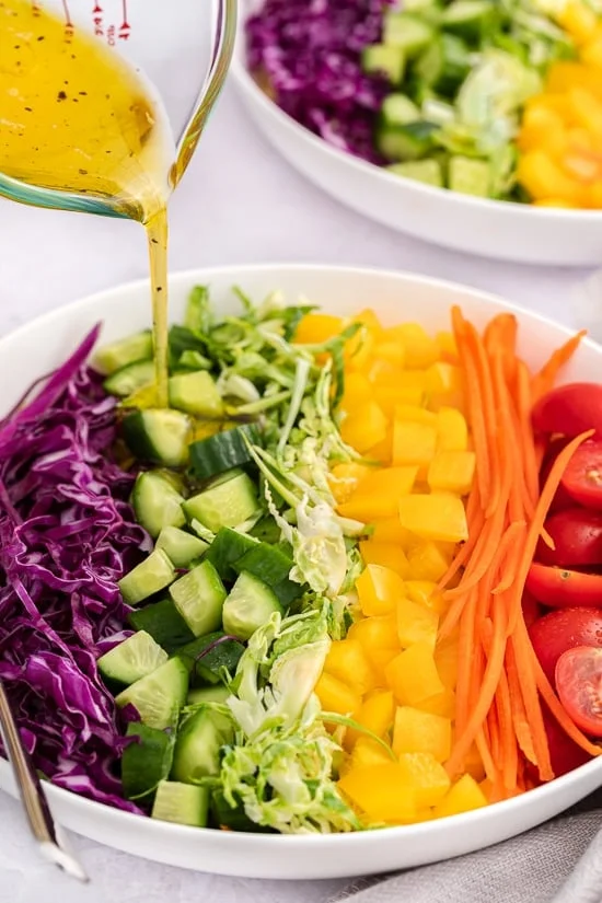 Rainbow Quinoa Salad pouring Lemon Salad Dressing