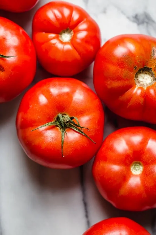 Ripe beefsteak tomatoes on marble countertop.