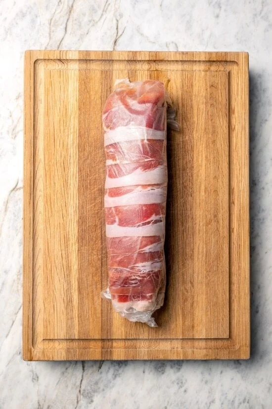 Turkey tenderloin wrapped in prosciutto and layer of plastic wrap.