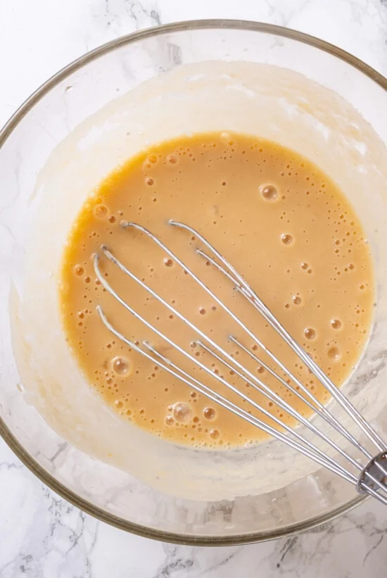 Wet ingredients in glass bowl with whisk
